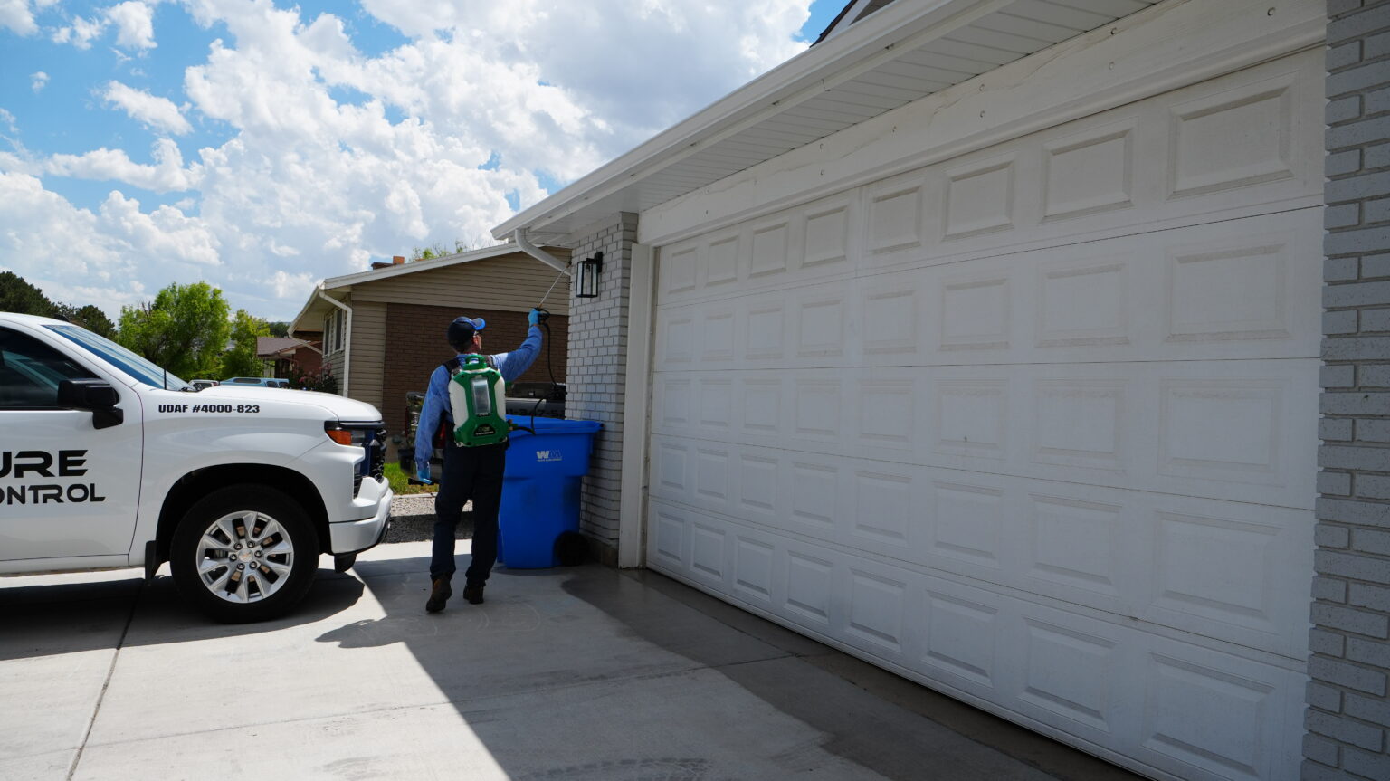 Signature Pest Control technician spraying around a garage